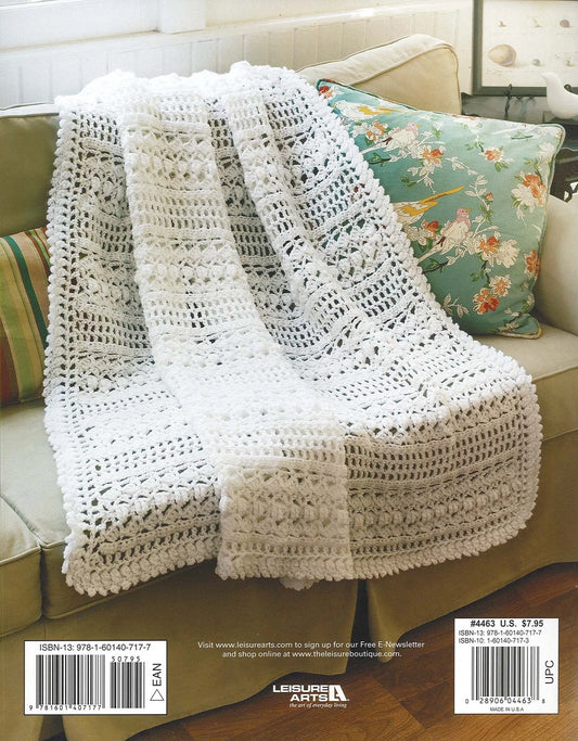 White crocheted blanket draped over a beige couch with floral cushions.