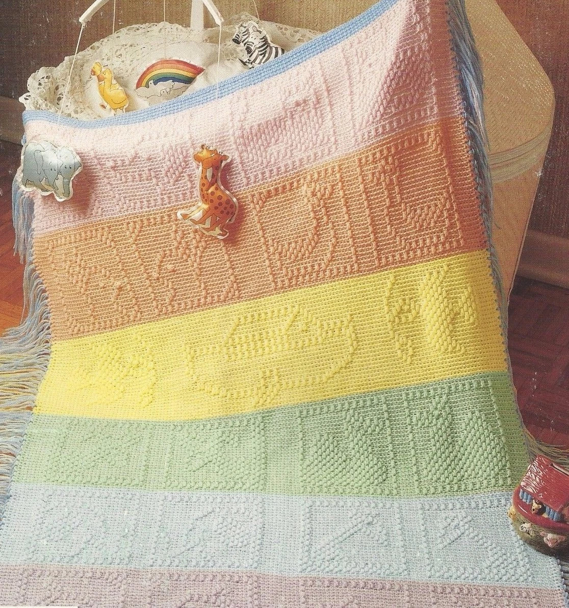 Colorful knitted baby blanket with toys on a wooden surface