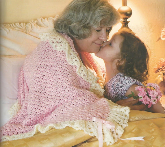 Woman and child hugging under a pink blanket with a floral arrangement.