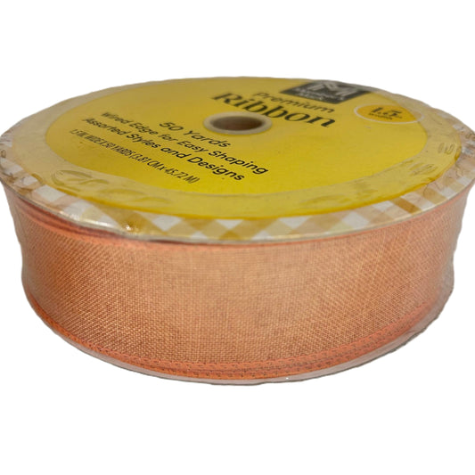 Spool of peach-colored ribbon with a yellow label on a white background