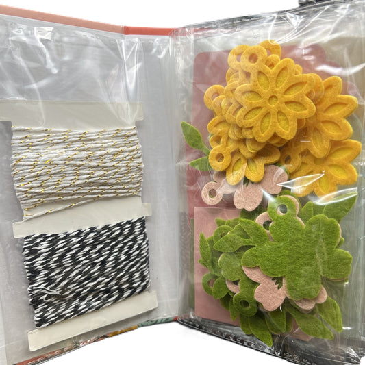 Bag of felt flower designs and white and gold thread and black and white thread.
