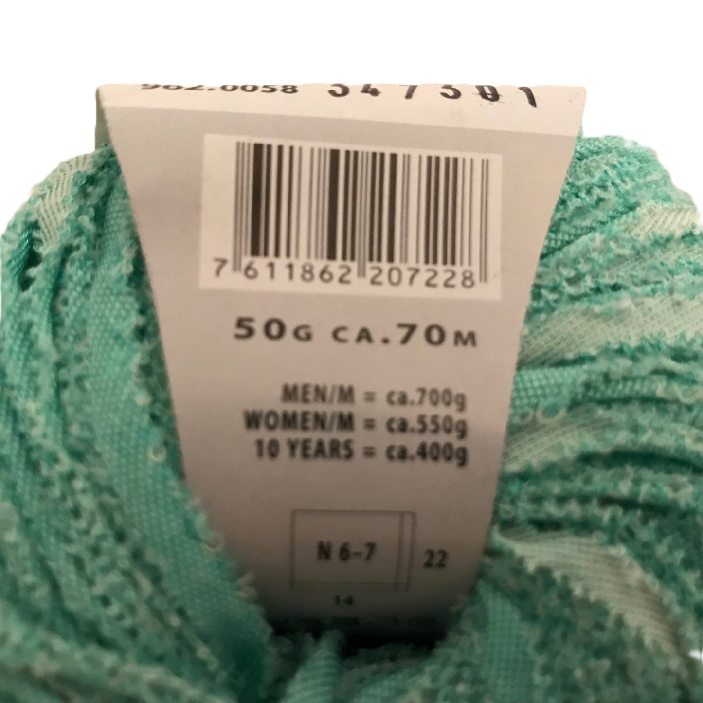 Green yarn with a label showing weight and size information on a white background