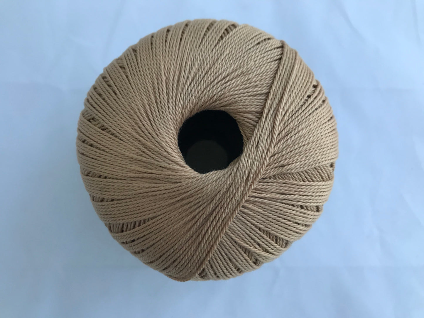 Ball of beige yarn on a light blue background