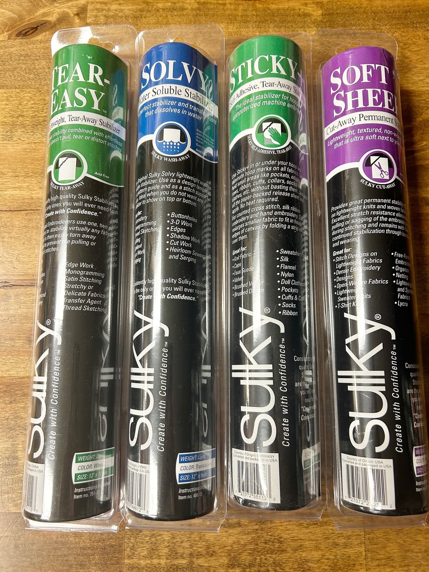 A high-quality image of four rolls of Sulky brand sewing and embroidery stabilizer products: Tear-Easy, Solvy water-soluble, Sticky self-adhesive tear-away, and Soft 'n Sheer cut-away.