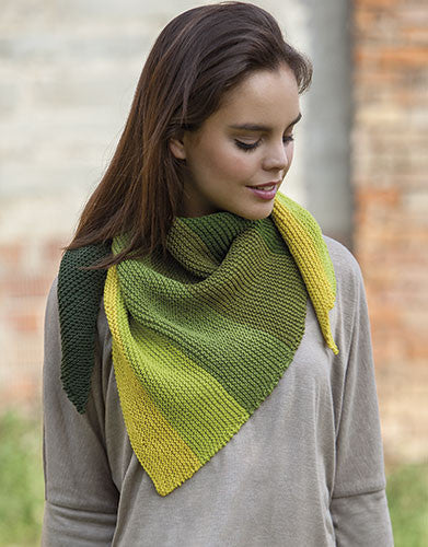 Woman wearing a green and yellow knitted shawl outdoors.