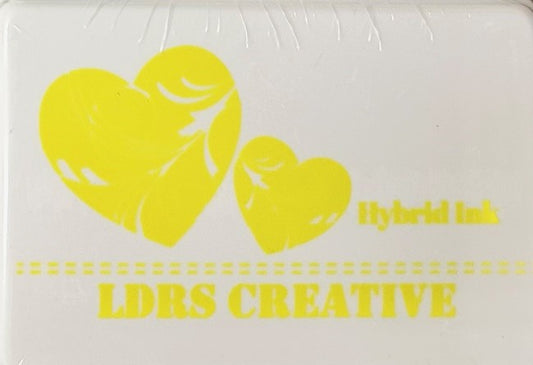 An image of a white ink pad featuring two yellow hearts with white decorative swirls and the text "LDRS CREATIVE Hybrid Ink" and the color name "Lantern Yellow" in yellow.
