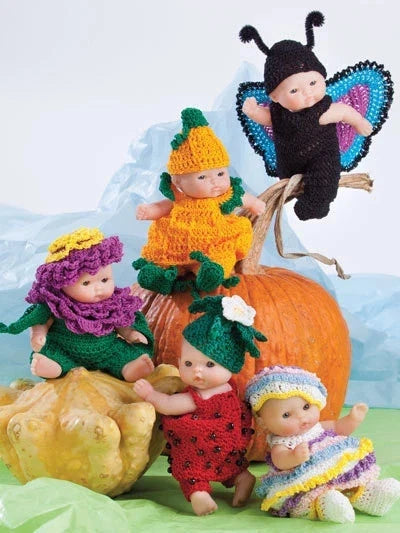 Toy babies in colorful outfits and hats on pumpkins against a light blue background