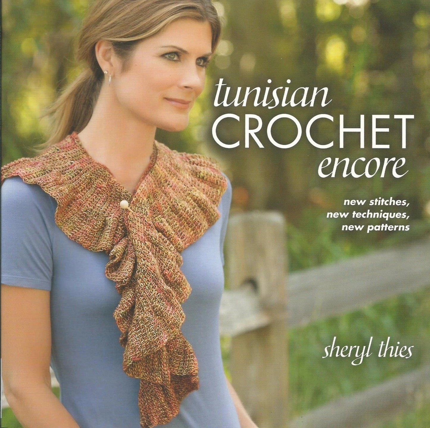 Book cover of 'Tunisian Crochet Encore' by Sheryl Thies featuring a woman wearing a crocheted scarf.