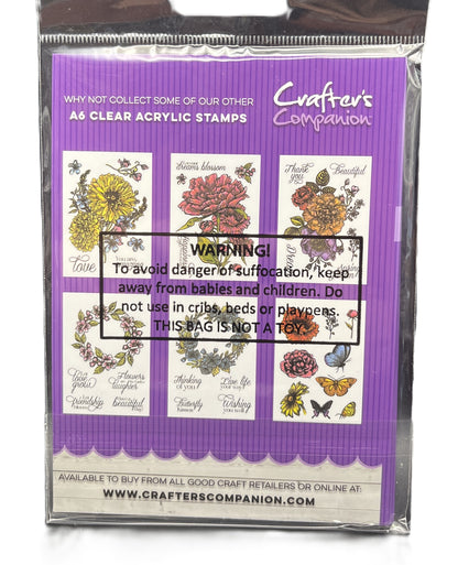 Packaged clear acrylic stamps with floral designs and warning label on purple background