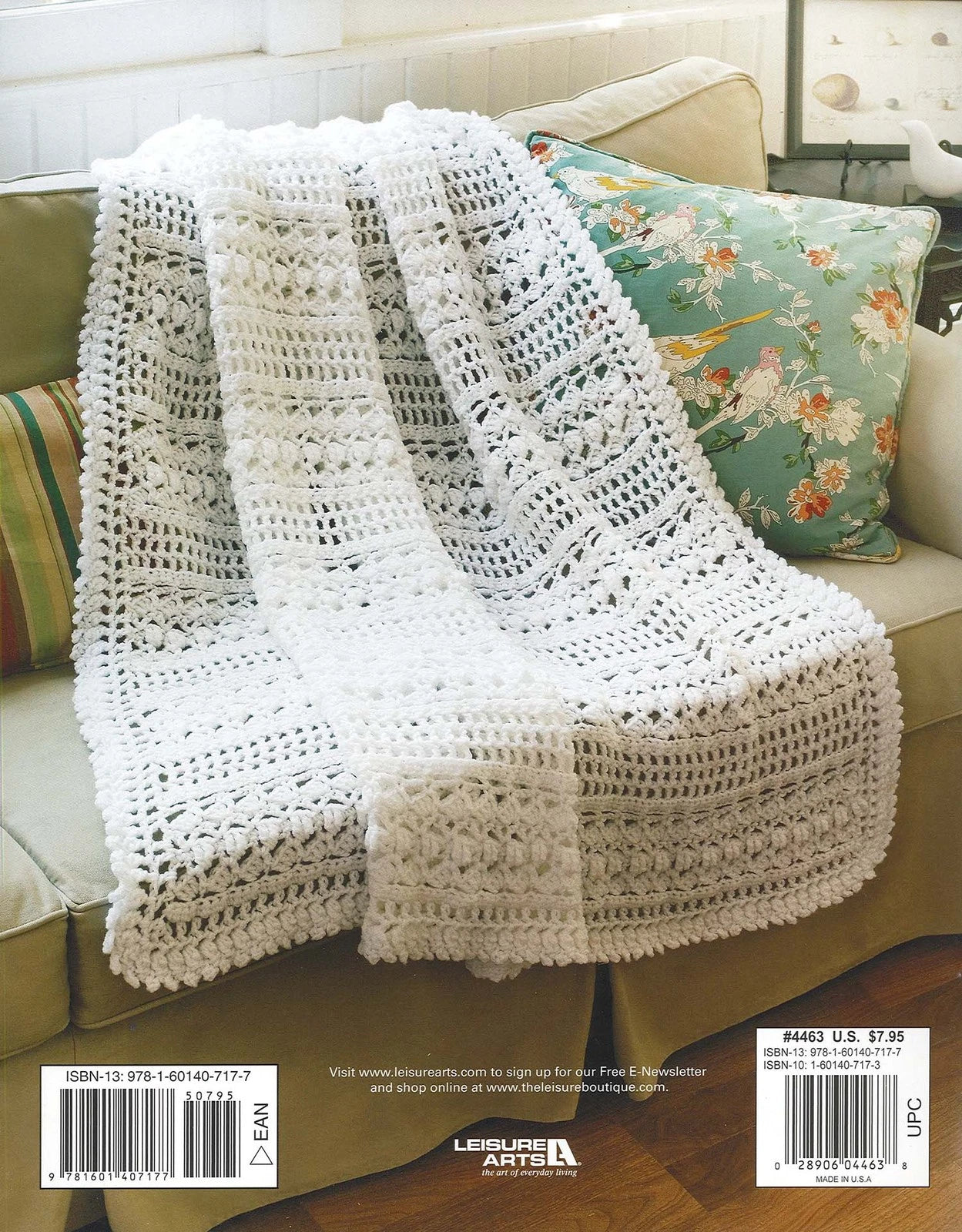 White crocheted blanket draped over a beige couch with floral cushions.