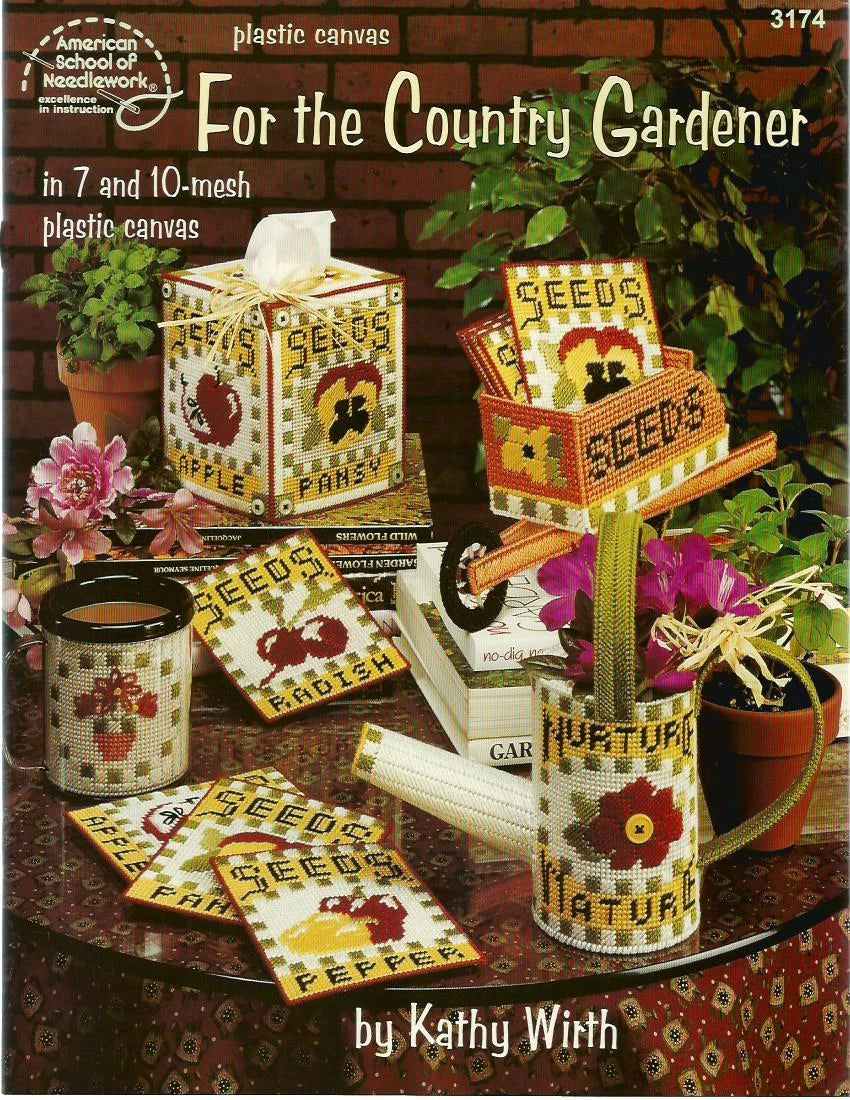 Plastic canvas patterns for garden-themed items including a seed box, watering can, and coasters on a table with plants and flowers.