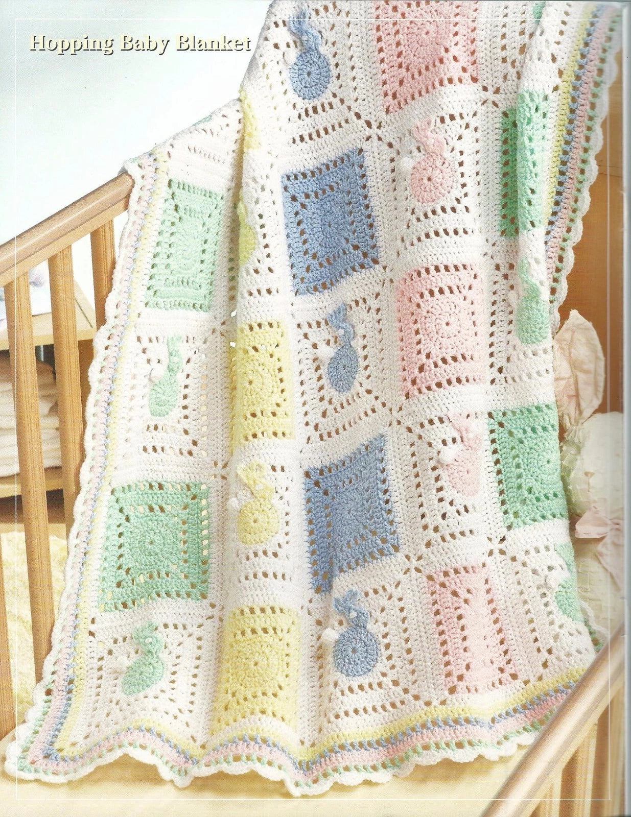 Crocheted baby blanket with colorful squares draped over a crib.
