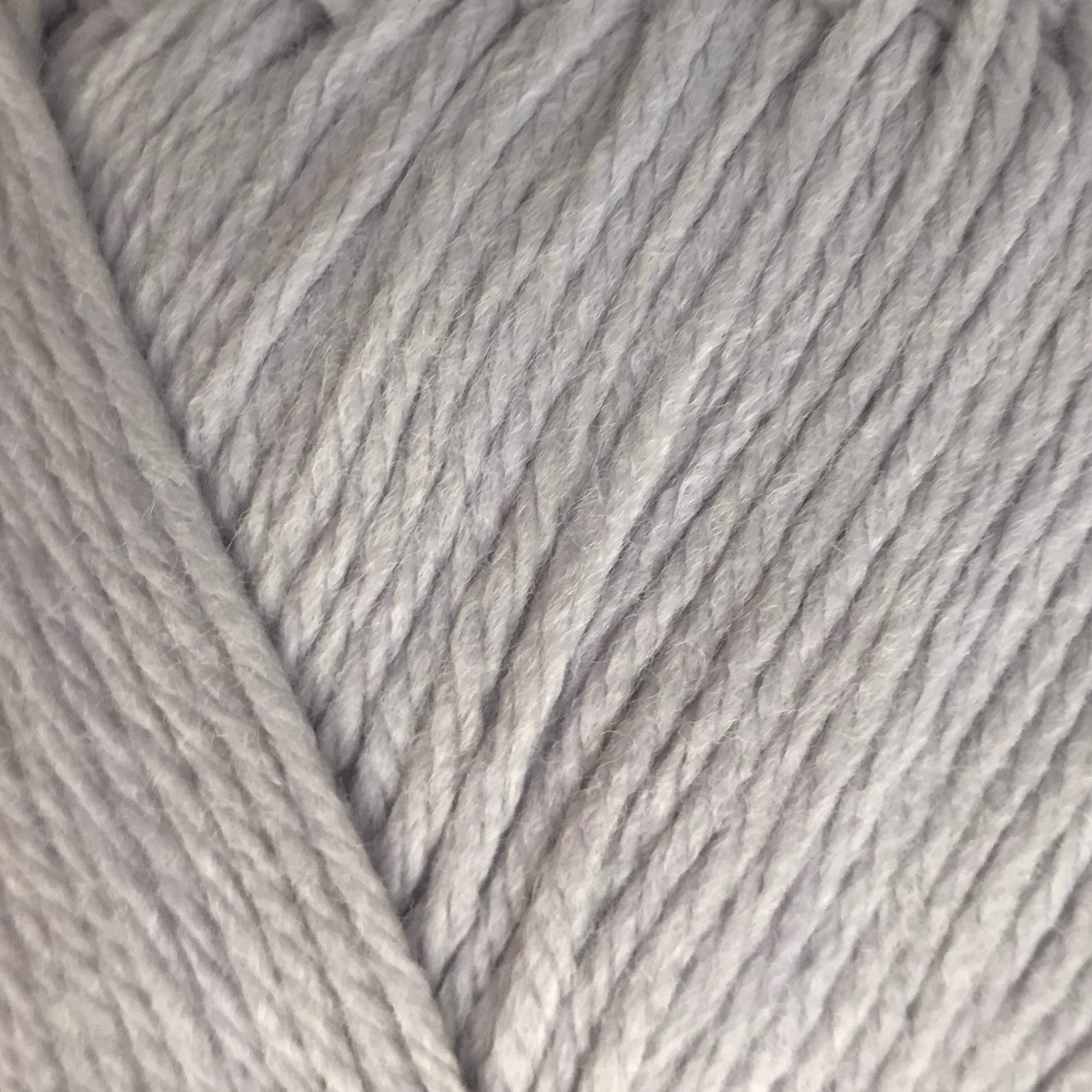 Ball of light gray yarn on a beige background