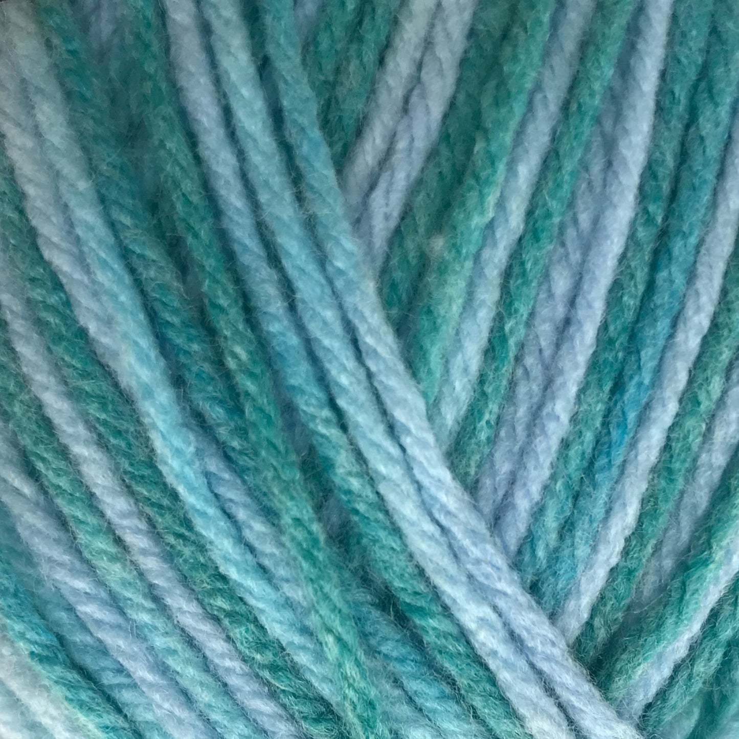 Ball of yarn with a gradient of blue and green on a light gray background