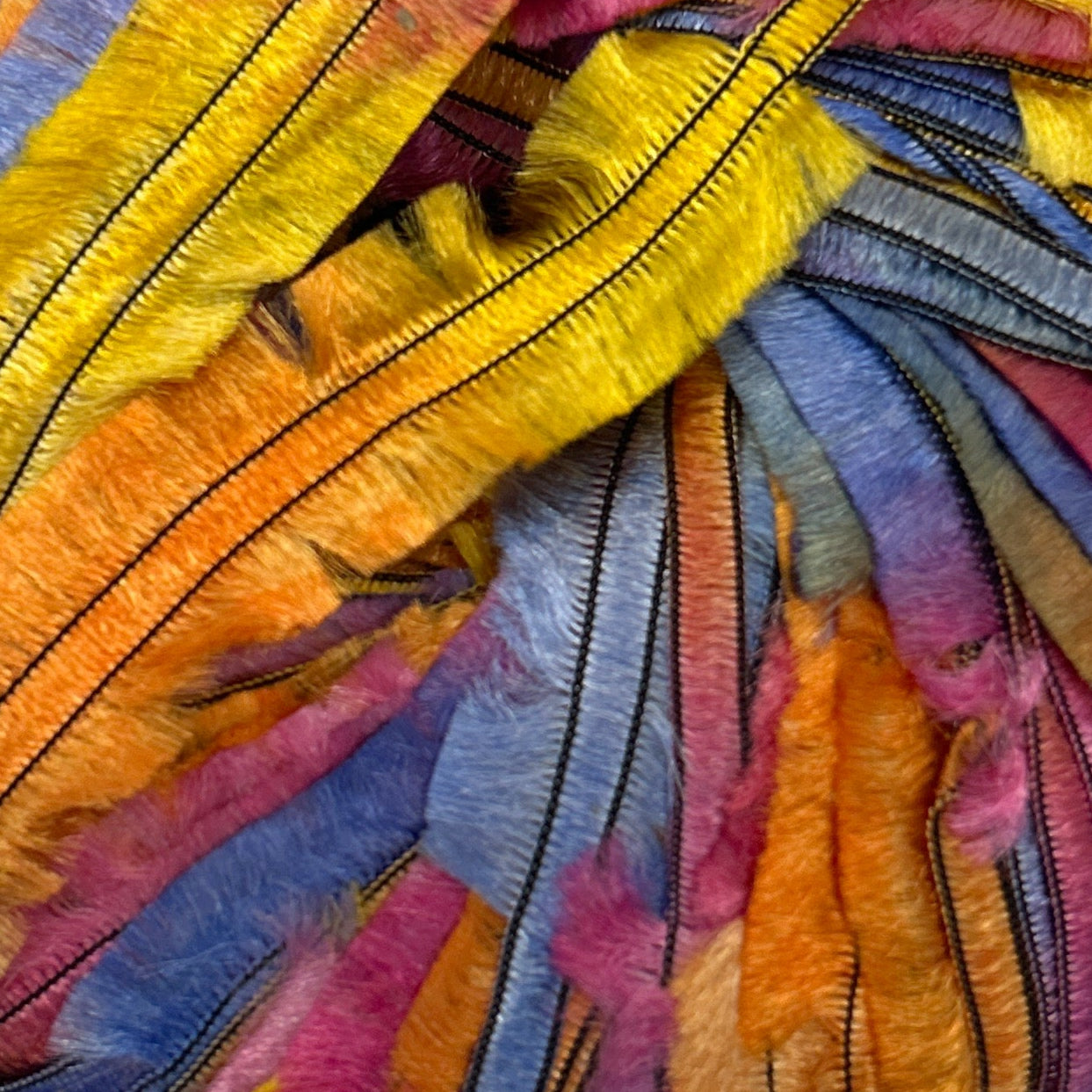 Close-up of colorful fabric with embroidery in various shades of yellow, blue, pink, and orange.