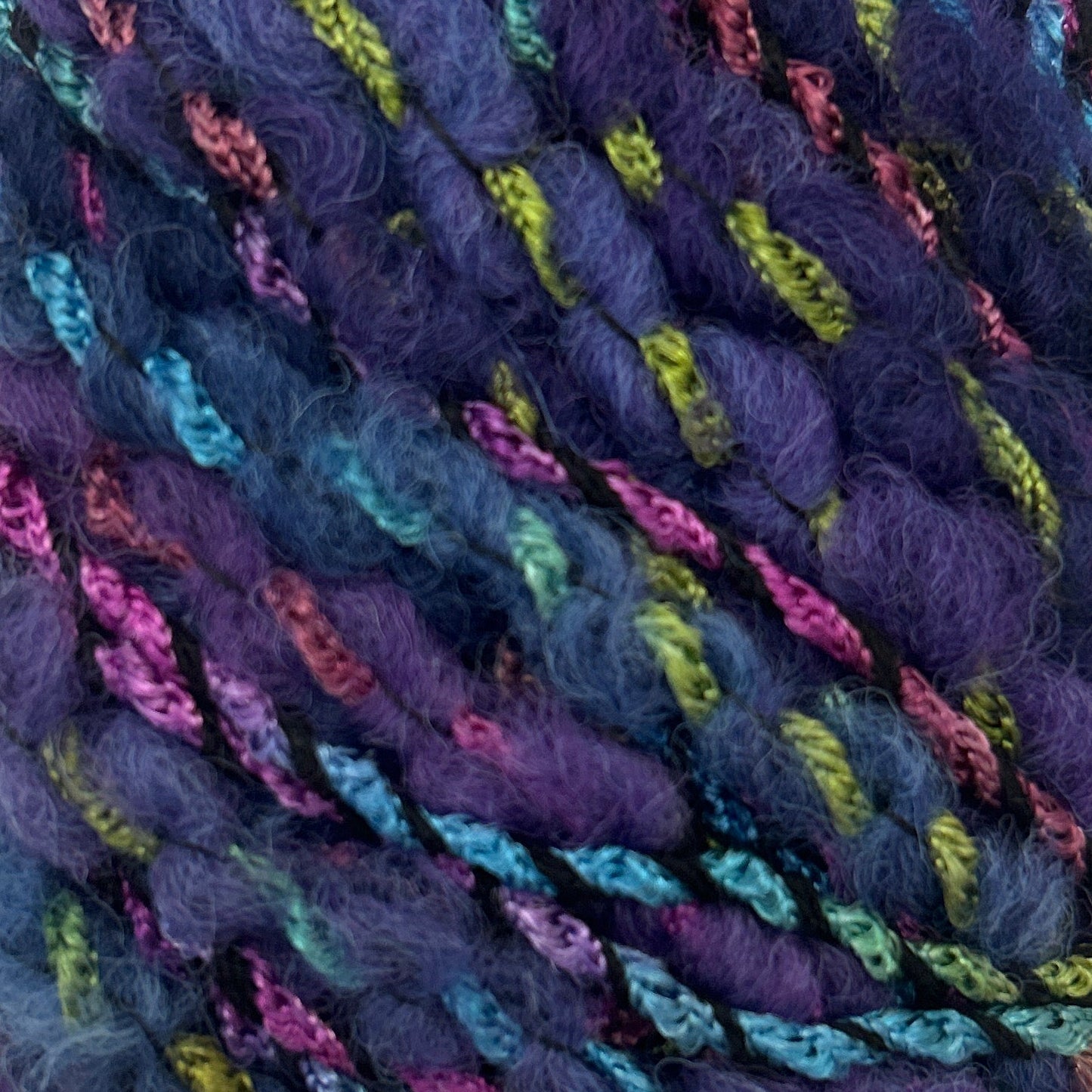 Close-up of multicolored yarn skeins with a purple hue.