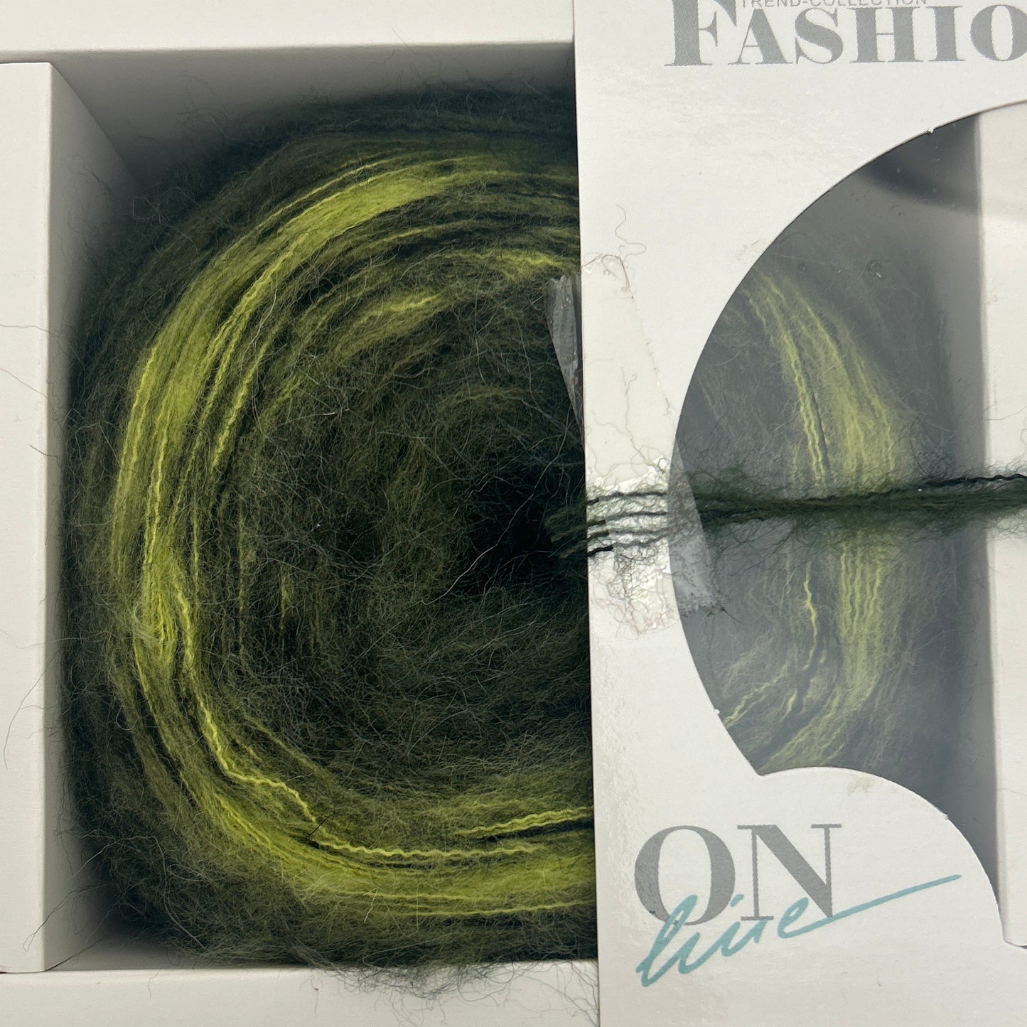 Green skein of yarn in a clear plastic packaging with visible branding on a light gray background