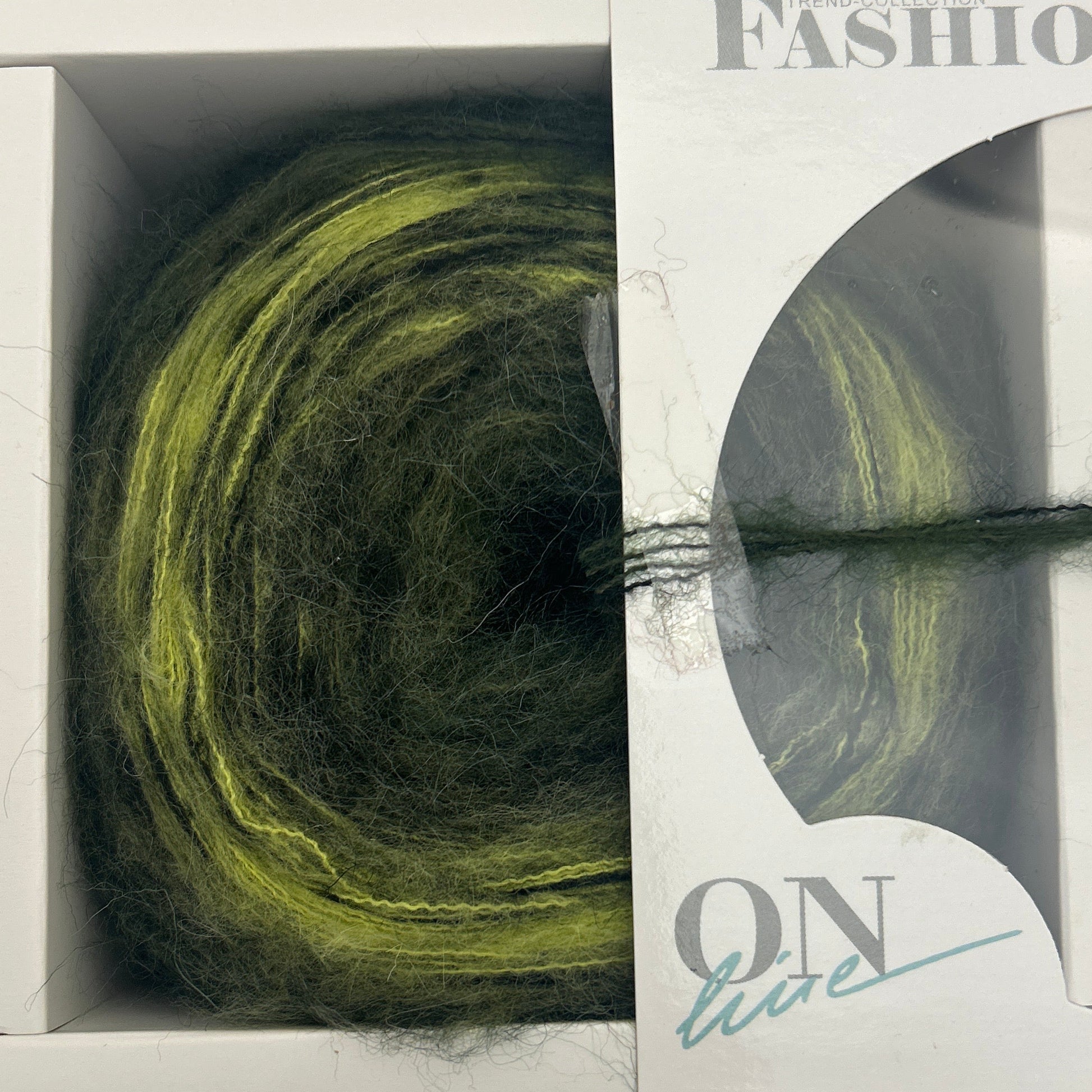 Green skein of yarn in a clear plastic packaging with visible branding on a light gray background