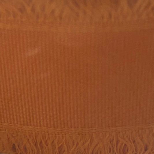 Close-up of a textured orange fabric with frayed edge