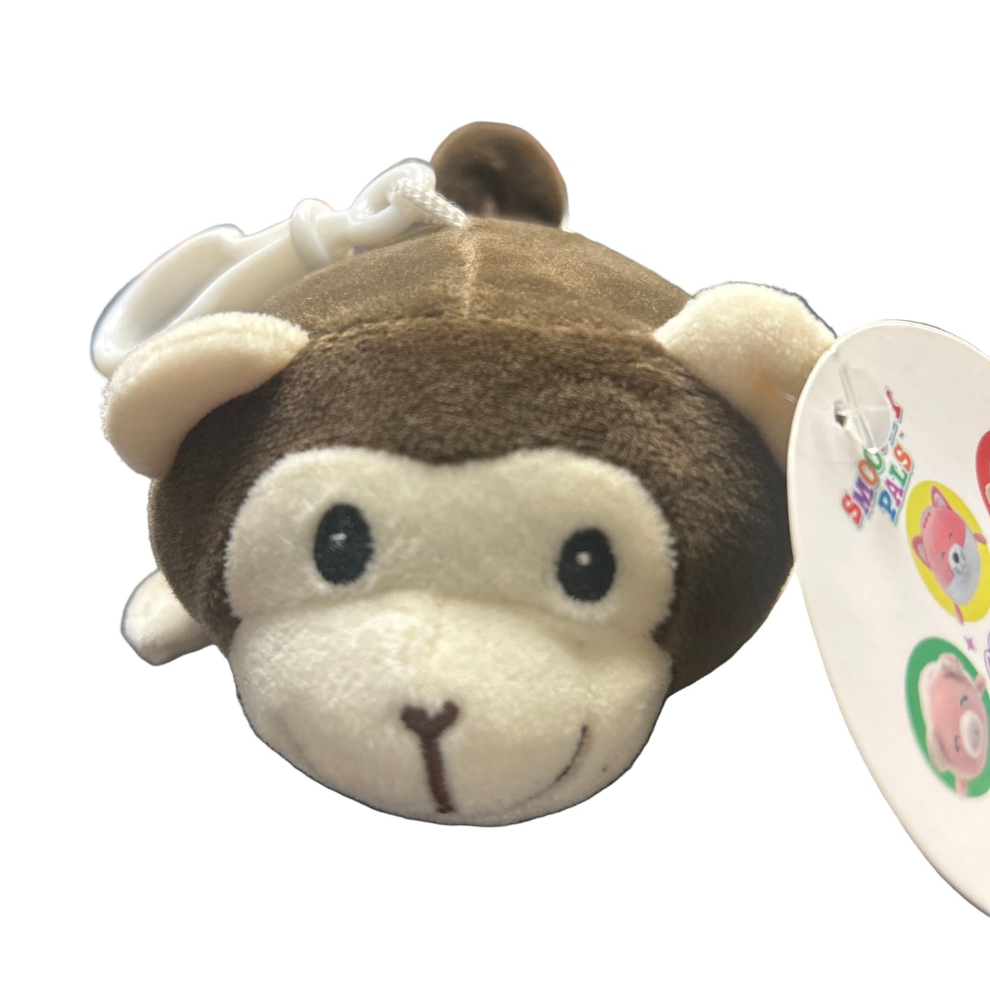 Plush monkey toy with a tag on a dark surface