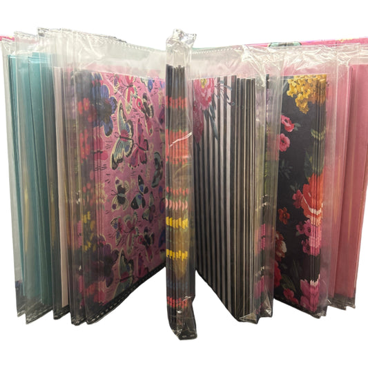 Stack of colorful books or notebooks with floral patterns on a gray surface