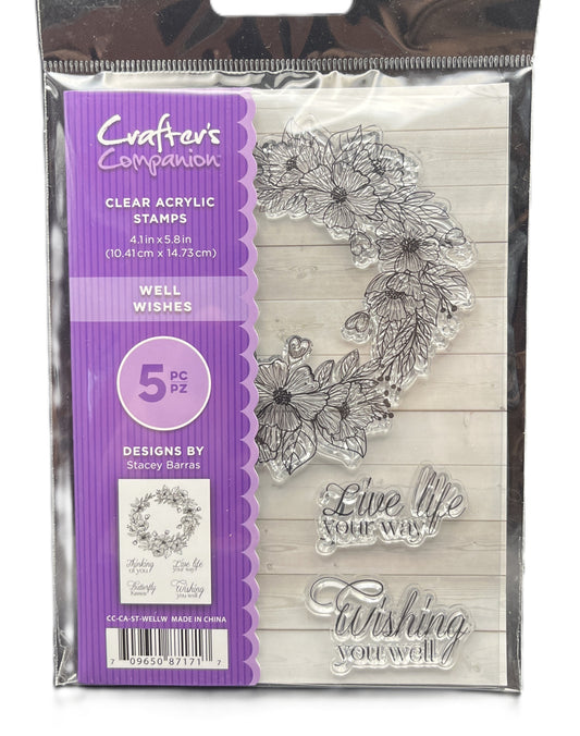 Packaging of clear acrylic stamps with floral designs and text on a wooden background.