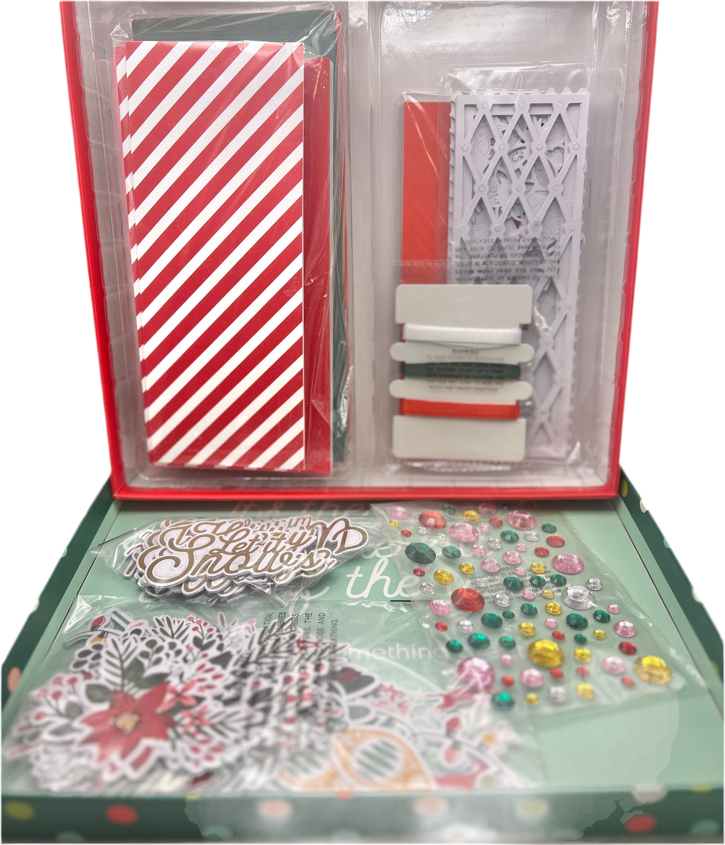 Packaged craft items including a red and white striped card, decorative elements, and embellishments on a green base.