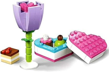 Toy set with a tulip, heart-shaped box, and small cake on a white background