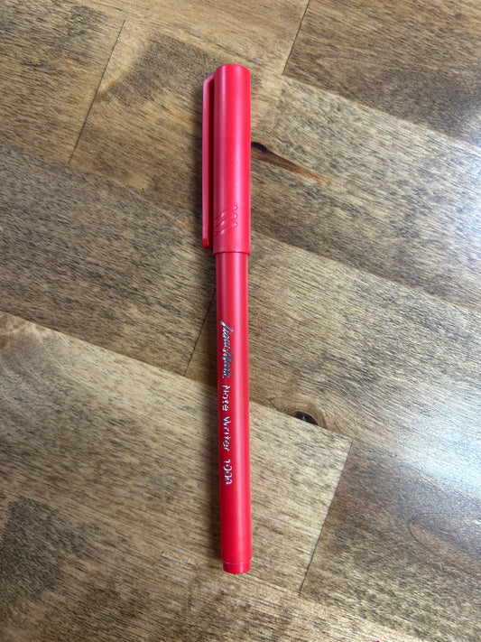 Red pen on a wooden surface