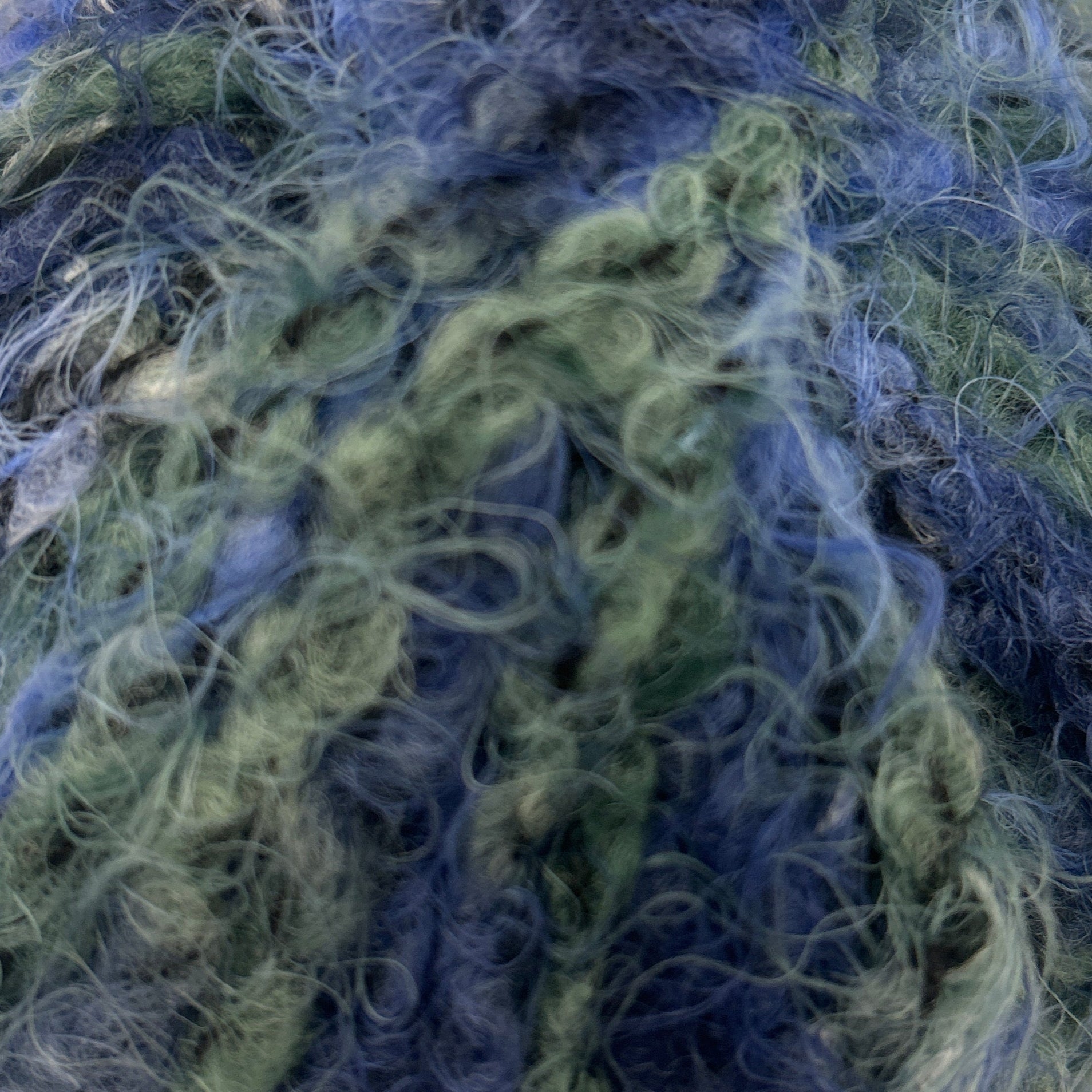 Ball of blue and green yarn on a white background