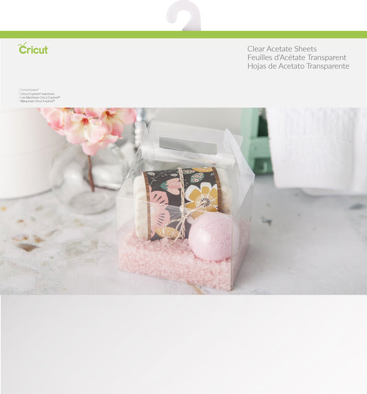 Cricut clear acetate sheets packaging with a decorative box and flowers on a marble surface.