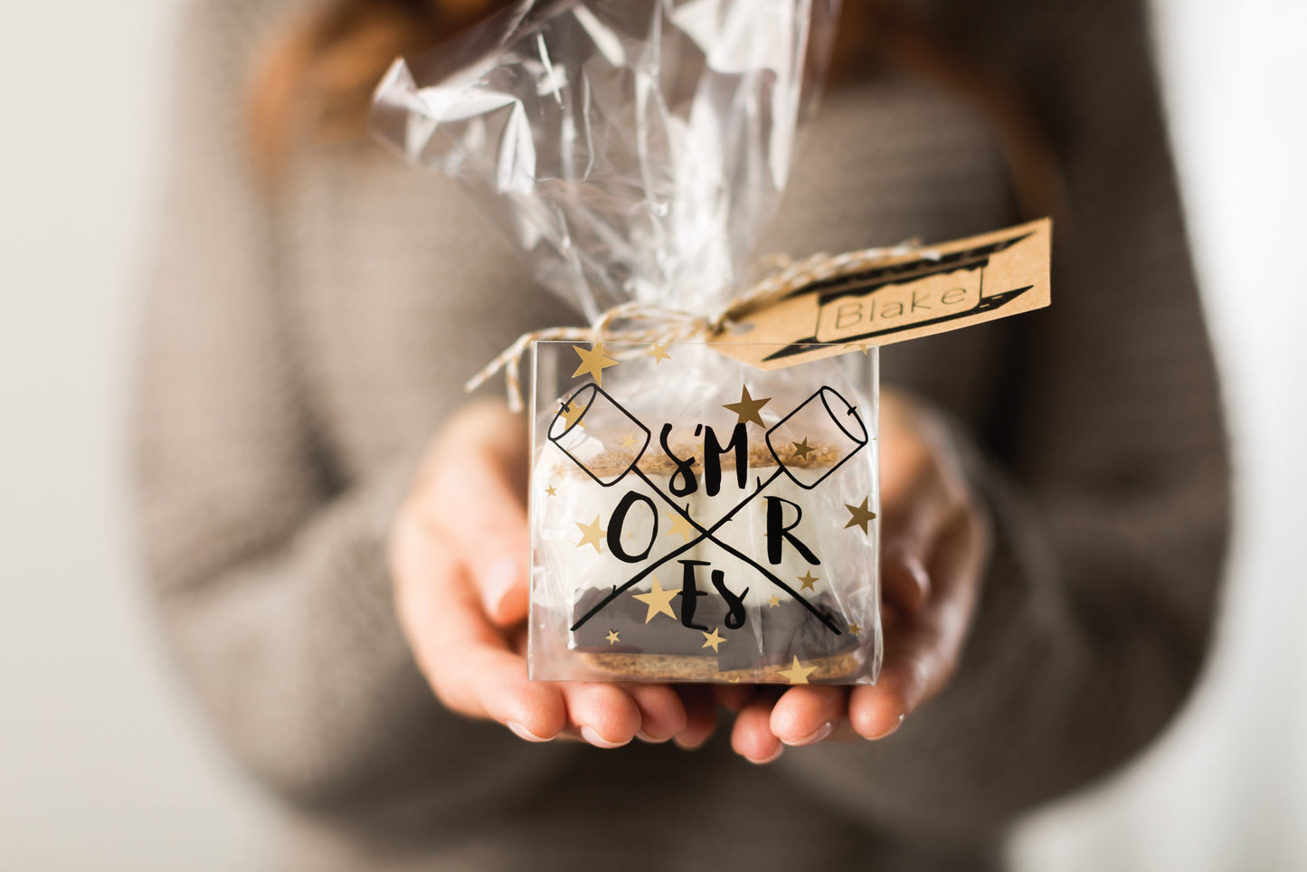 Person holding a clear gift bag with decorative text and stars.