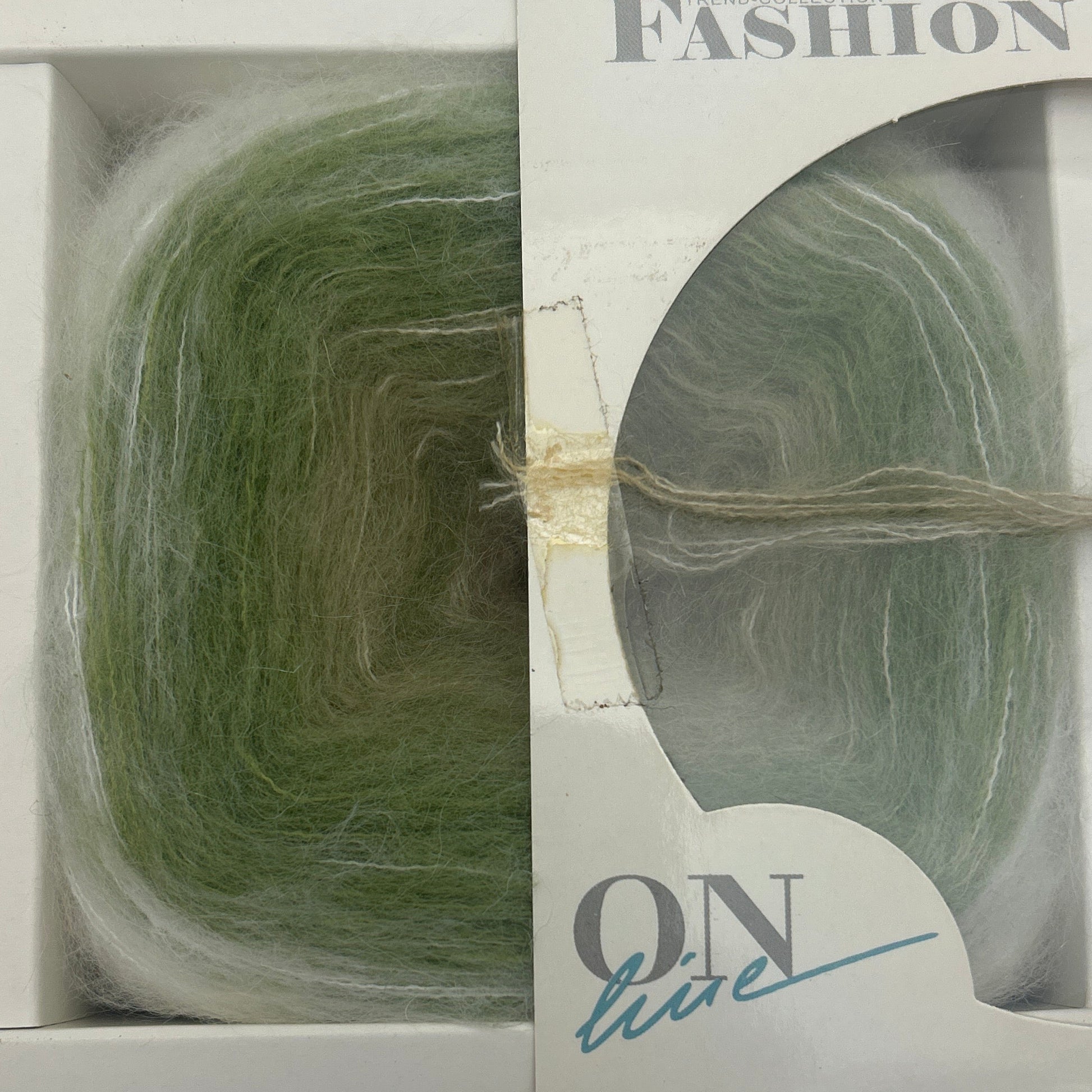 Green yarn skein in a clear plastic packaging with visible brand name on a white background