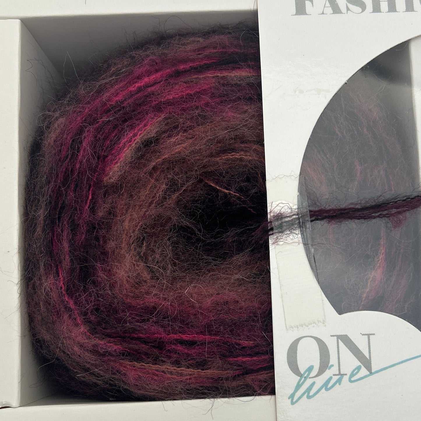 Ball of purple yarn in a packaging box with visible brand name.