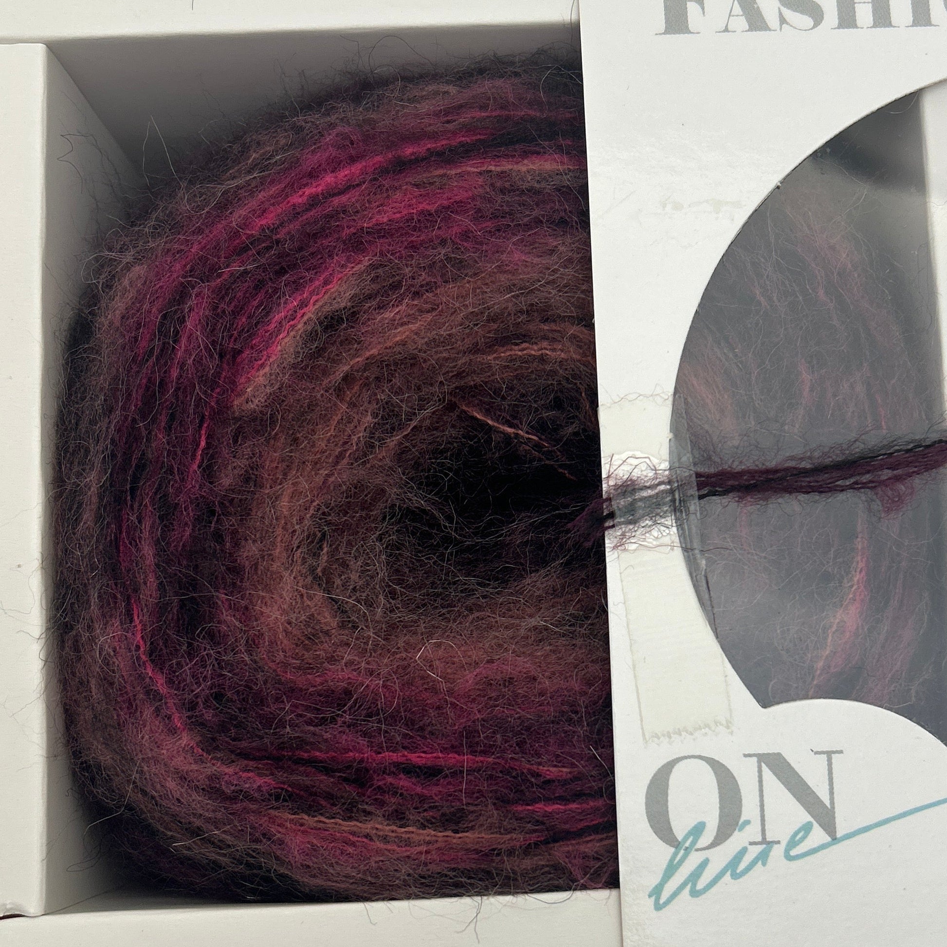 Ball of purple yarn in a packaging box with visible brand name.