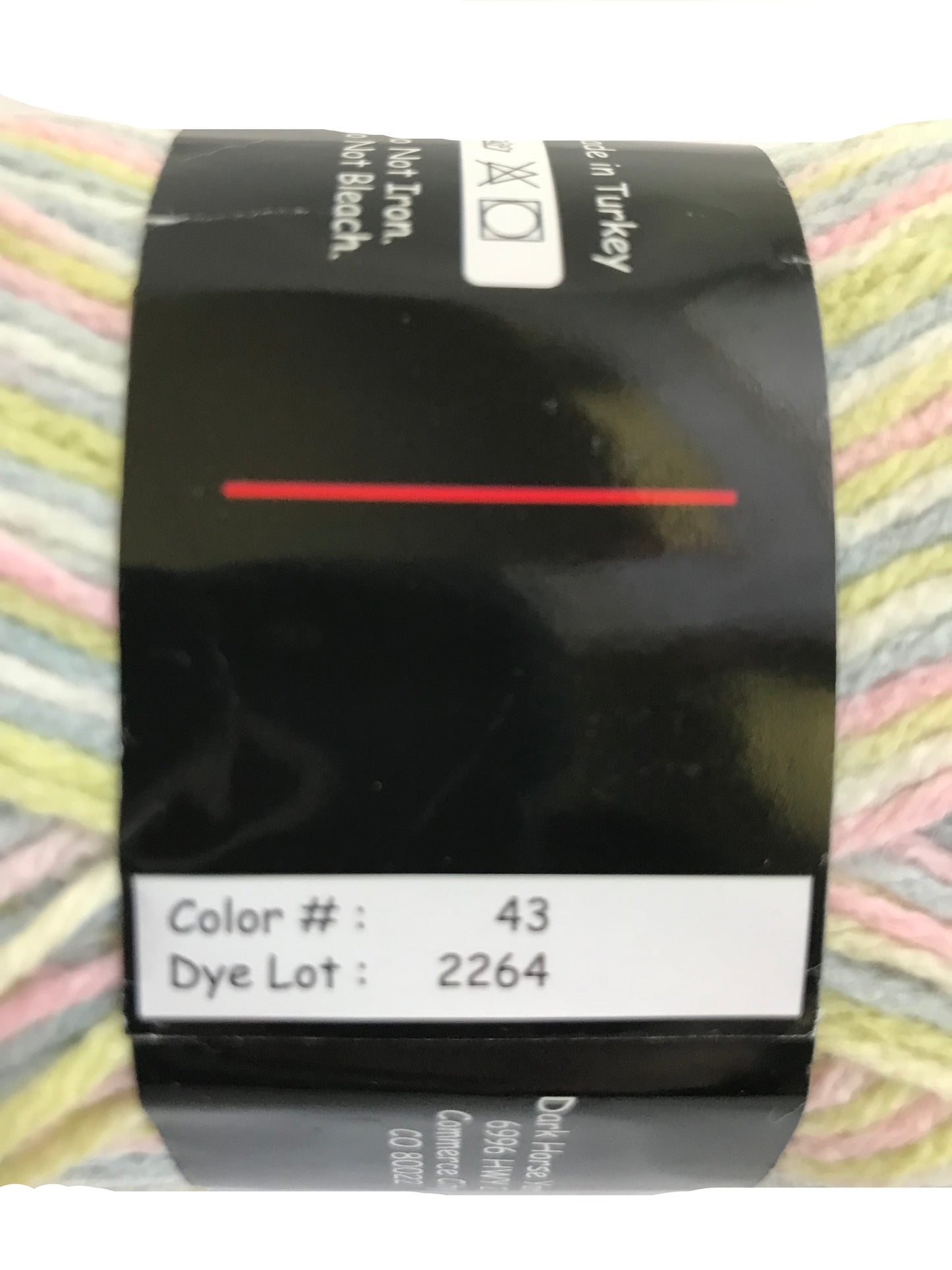 Yarn ball with a label showing color number 43 and dye lot 2264, against a blurred background.
