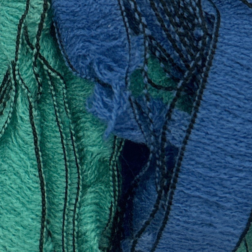 Close-up of textured fabric with blue and green colors and black stitching.