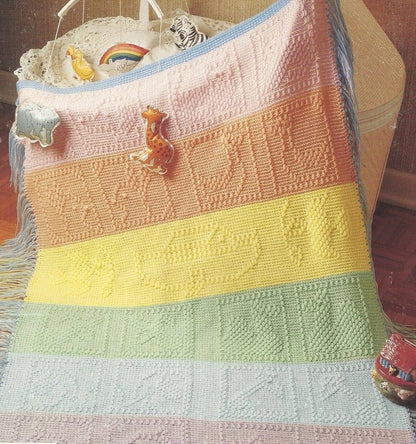 Colorful knitted baby blanket with toys on a wooden surface