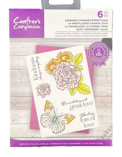 Packaging of Crafters Companion stamps with floral and butterfly designs on a wooden surface.