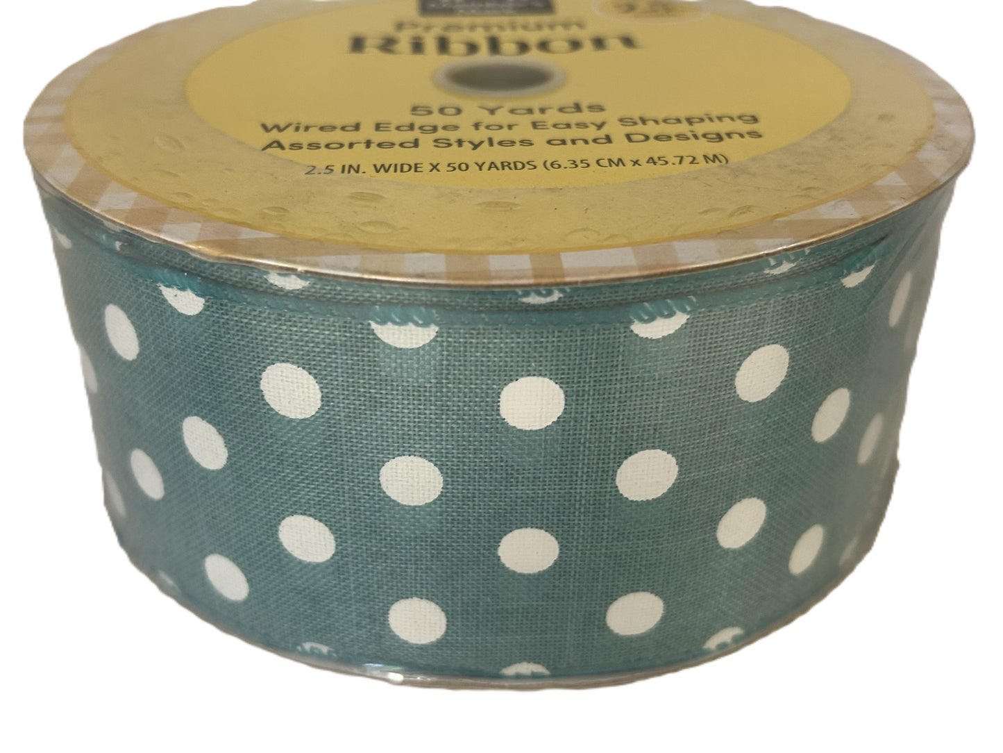 Spool of green ribbon with white polka dots on a white background