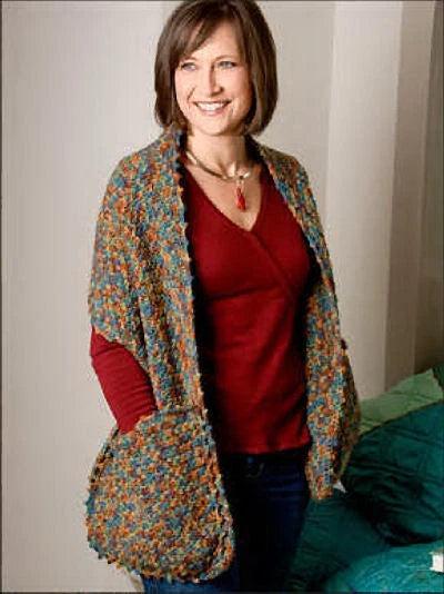 Woman wearing a colorful knitted cardigan over a red shirt, standing against a neutral background.