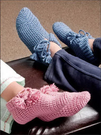 Blue and pink crocheted slippers on a person's feet.