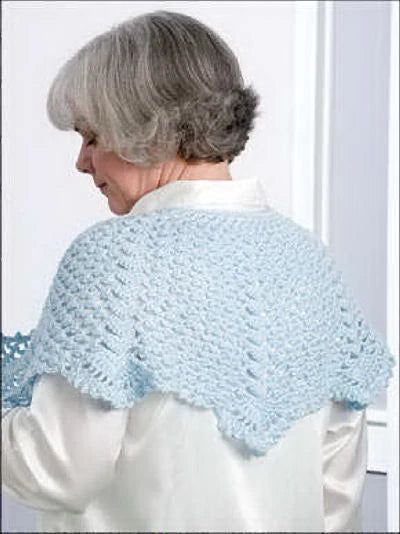 Woman wearing a light blue knitted shawl against a white background