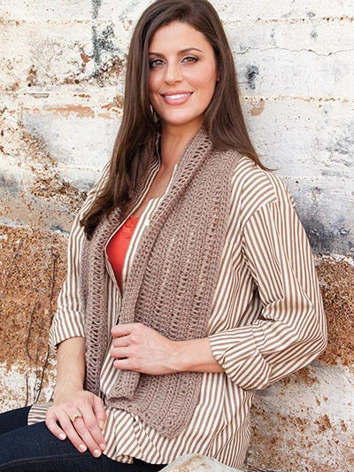 Woman wearing a brown and beige striped cardigan against a textured wall.