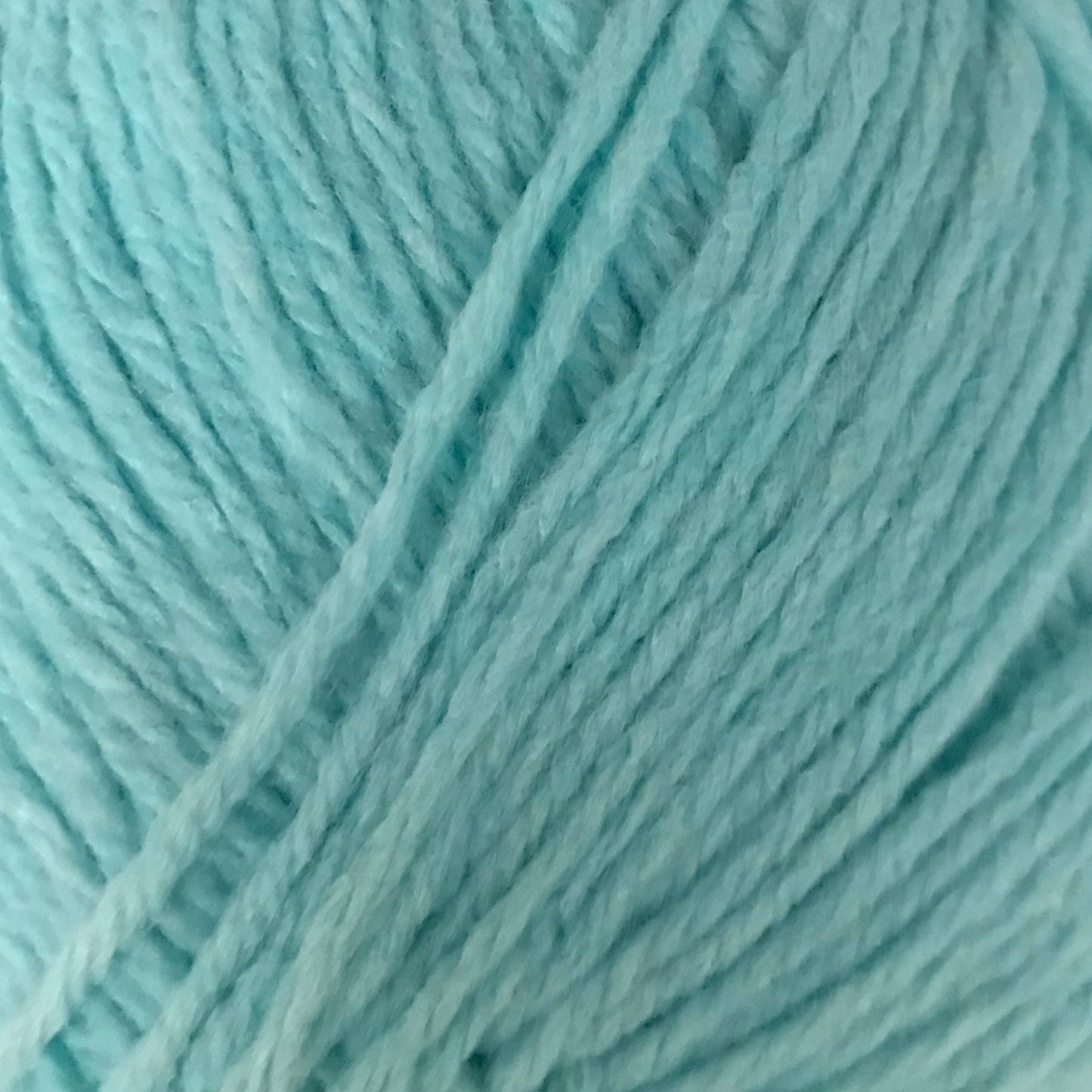 Turquoise skein of yarn with a label on a light gray background