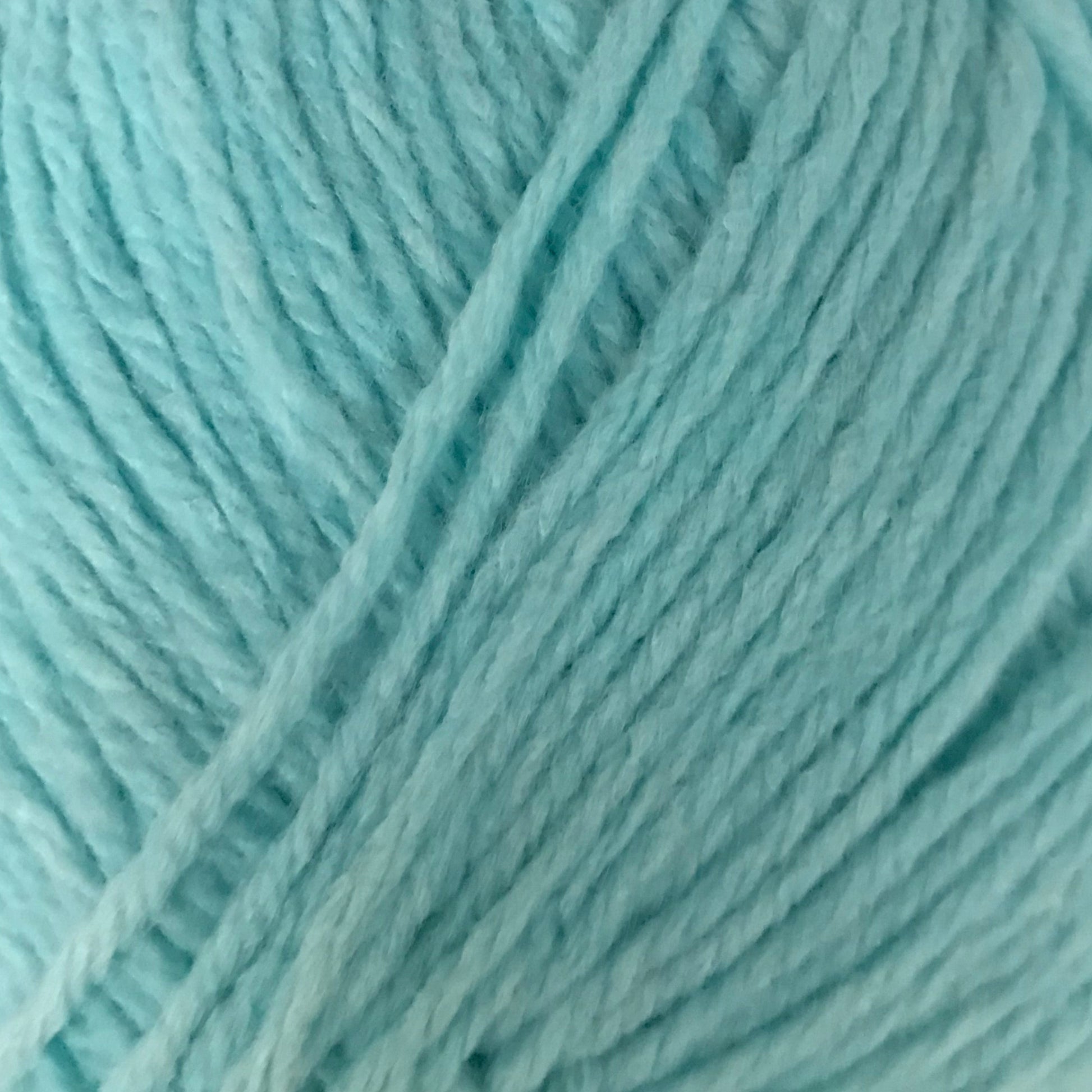 Turquoise skein of yarn with a label on a light gray background