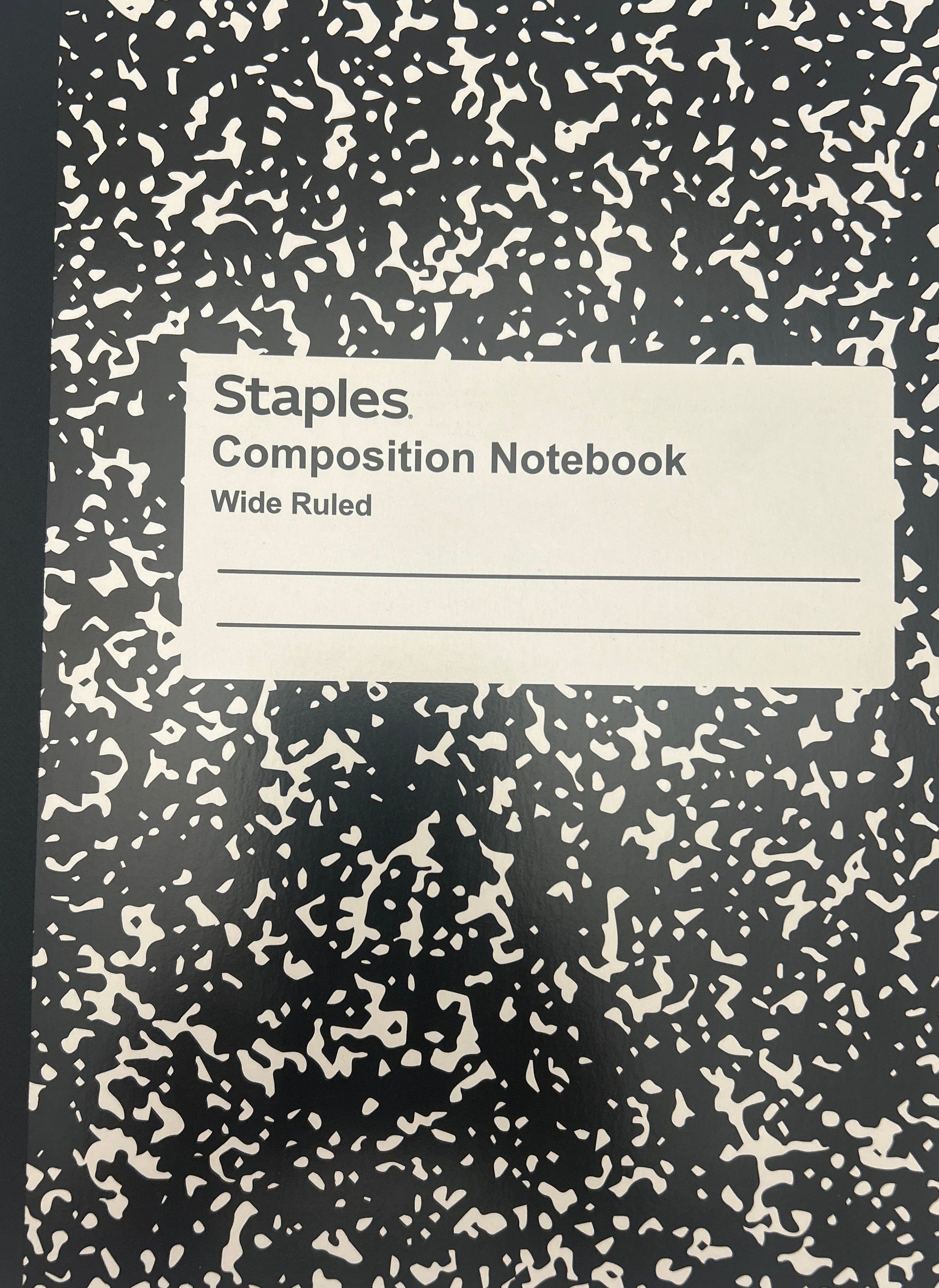Black composition notebook with white speckled pattern on a light gray background