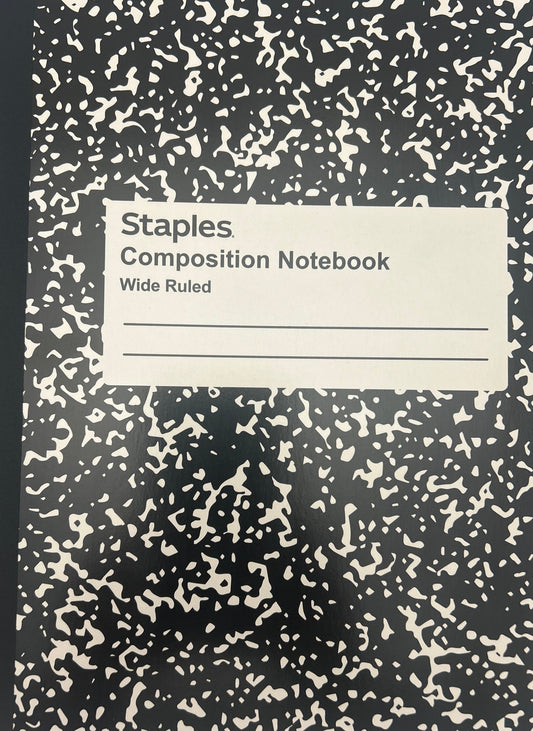 Black composition notebook with white speckled pattern on a light gray background