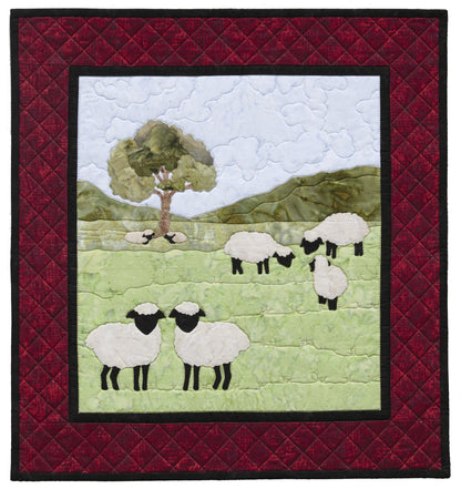 Quilt with sheep and tree design on a red border