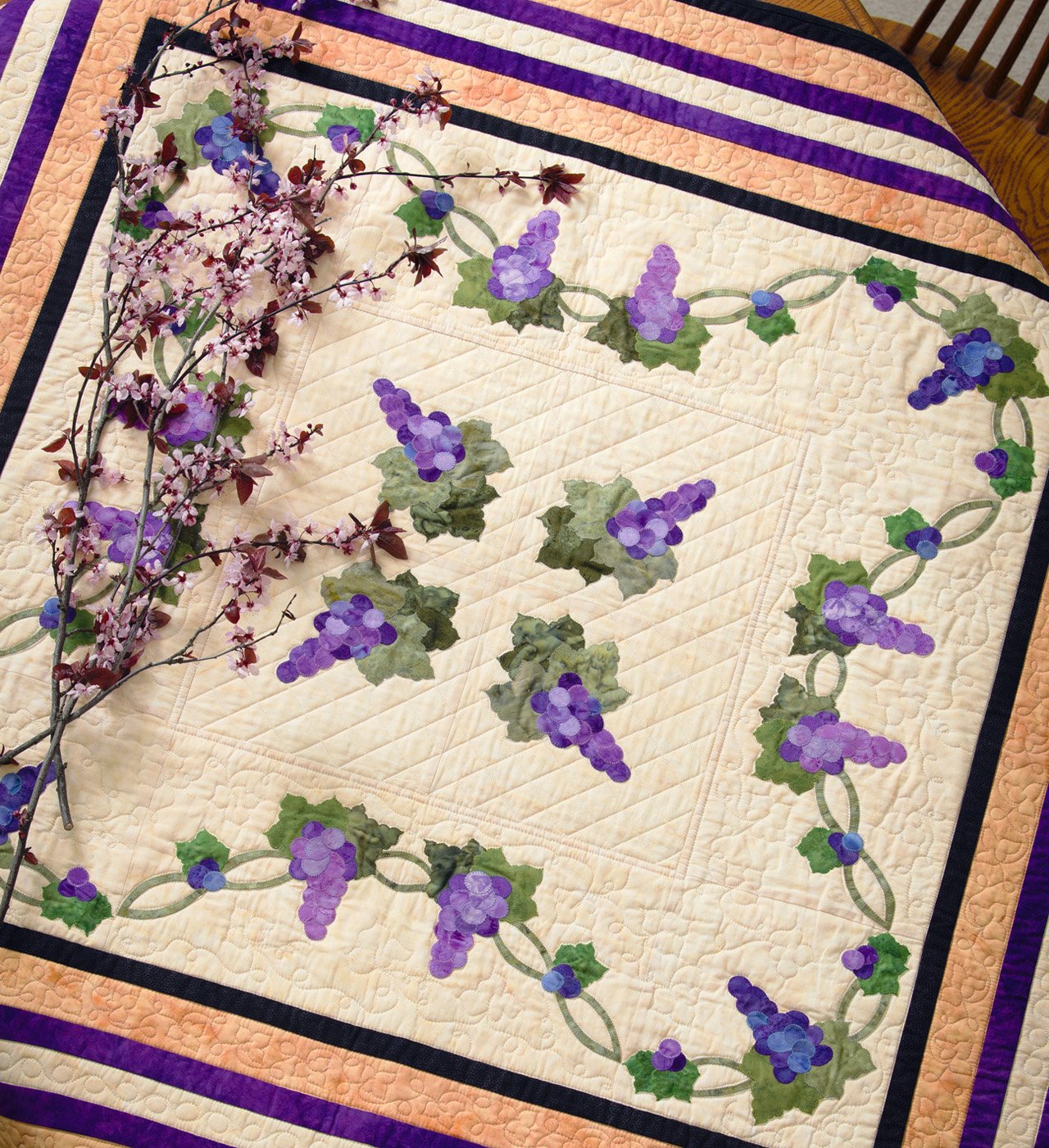 Quilt with grapevine design and purple flowers on a wooden surface